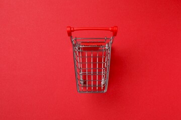 Small silver shopping cart on red background, top view © Sunlight