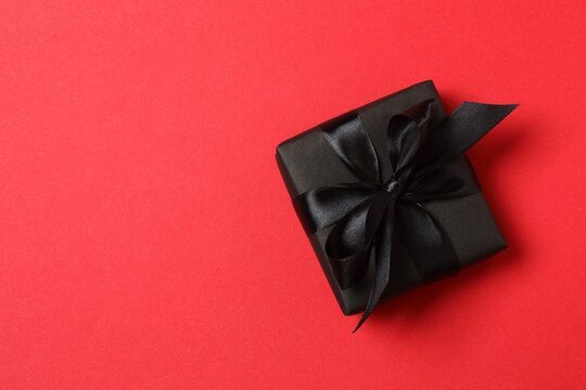 Top view of black gift box against a red background. Space for text