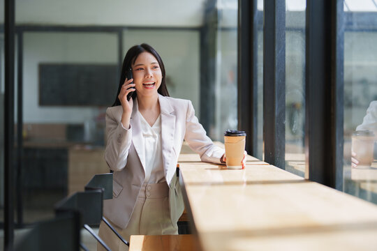Businesswoman talking on smartphone holding coffee cup