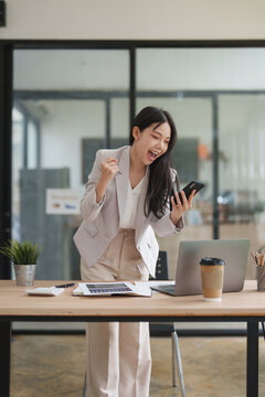 Excited businesswoman receiving good news on smartphone