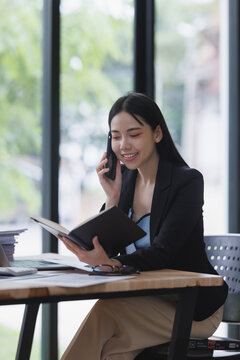 Businesswoman talking on smartphone and reading notebook