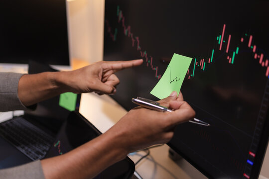Professional stock trader reviewing market charts with sticky notes across multiple monitors, laptop, and tablet to analyze price trends, plan trading strategies, and manage investment decisions.