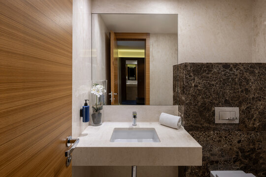 Modern bathroom vanity interior with marble counter mirror and wooden door