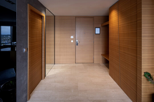 Modern hotel suite entrance hall with wooden panelling and stone flooring