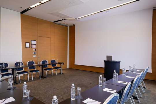Modern conference room set up for presentation with projection screen and podium