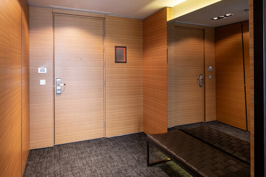 Modern luxury hotel room entryway with wooden walls and mirrored wardrobe