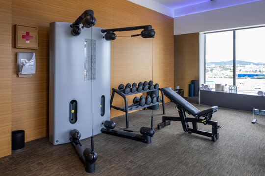 Modern hotel gym interior with cable crossover machine dumbbells and bench