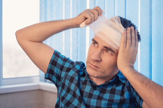 Injured man bandaging his own head, wound care, medical emergency, self-treatment.