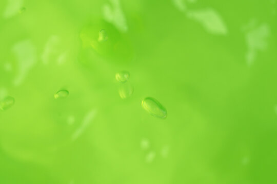 Macro shot of green aloe vera gel texture with air bubbles and light reflections, selective focus with copy space on green background for skincare cosmetics, hydration, and organic beauty products.