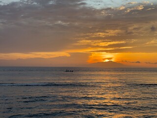 Obraz premium Golden sunset over ocean with small fishing boat silhouette
