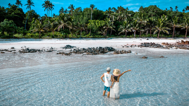 Couple tourist stay happy moment at the edge of the sea beach under shallow of the crystal clear water in summer trip on tropical island island