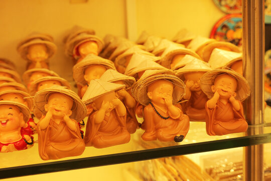 Traditional Vietnamese souvenirs featuring cute little wise monk figurines in conical hats on a shop shelf, Ho Chi Minh City, Vietnam.