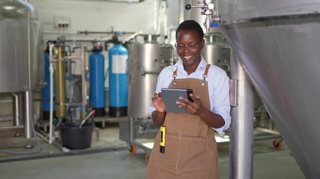 African woman brewer using a tablet in a modern brewery