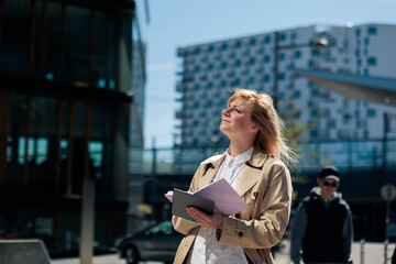 Fototapeta premium Businesswoman looking up planning in city with documents