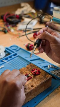 Vertical shot of engineer soldering wires to brushless motor on workbench. Footage is suitable for STEM education, robotics engineering, and DIY technology tutorials
