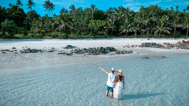 Couple tourist stay happy moment at the edge of the sea beach under shallow of the crystal clear water in summer trip on tropical island island