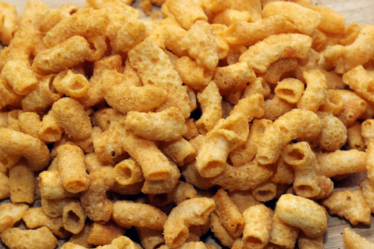 macro shot showcasing a dense pile of seasoned, golden-brown fried macaroni snacks with a crunchy texture.