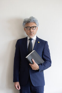 法律書を持って立つベテラン男性弁護士のポートレート
