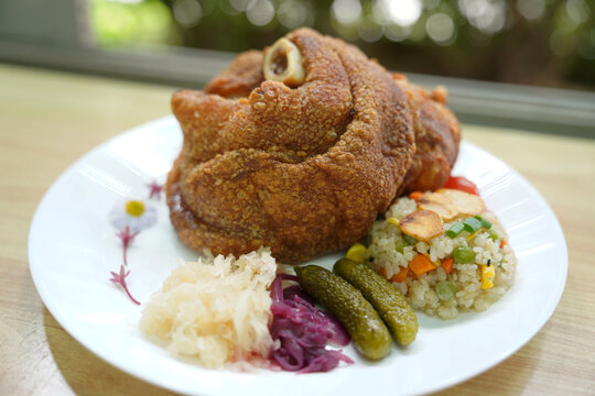 German pork knuckle with rice and garlic vegetables, served in the kitchen to restaurant customers.
