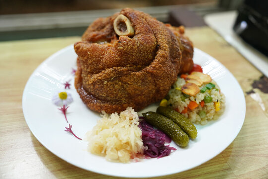German pork knuckle with rice and garlic vegetables, served in the kitchen to restaurant customers.
