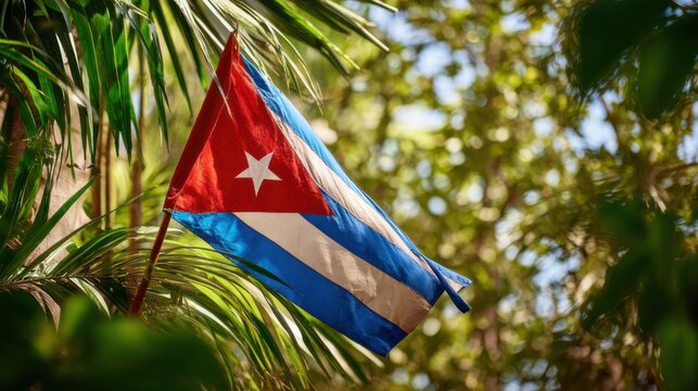 Cuban flag waving among green leaves in a natural setting during daylight hours showing national pride and culture