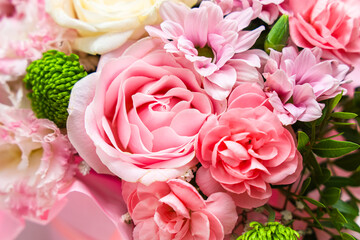 Fototapeta premium Colorful carnation flowers arranged in a bouquet with various types and shapes placed on a light surface