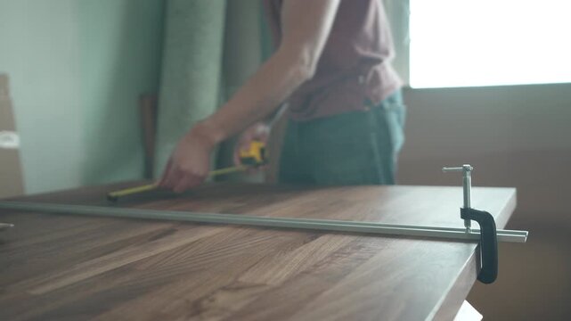 Man tightening a C-clamp to secure a metal guide rail on the edge of a walnut countertop