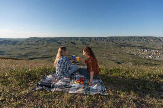Picnic, women, mountain, two female friends enjoying a scenic outdoor picnic with fruit and coffee on a sunny hillside landscape