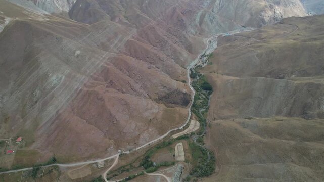 Reddish brown Chalus Road mountains frame a narrow green drainage line, an aerial highland panorama of arid Iranian terrain. Ideal for travel, tourism, and nature stock Iran Alborz valleys.