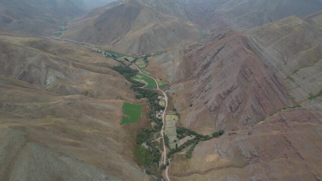 Aerial Chalus Road valley runs as a green ribbon between barren ridges, documenting Iranian mountain topography from above. Ideal for travel, tourism, and nature stock Iran Alborz mountains.