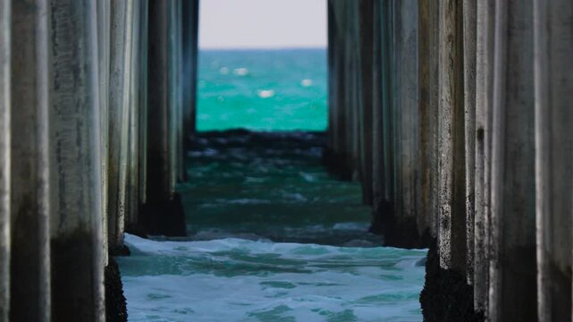 Slow moving waves breaking on the pier pylons and barnacles