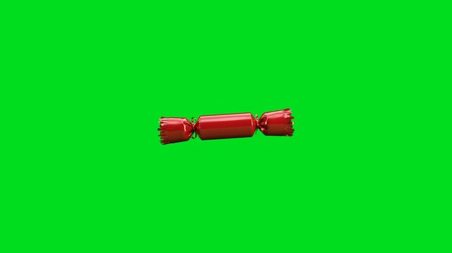 A single red candy wrapped in shiny foil isolated on a vibrant green background