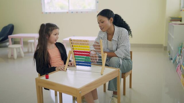 Young girl concentrates on colorful abacus with teacher beside her. Teacher smiles gently, guiding her through math learning