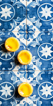 Portuguese egg custard tarts pasteis de nata on traditional blue and white azulejo ceramic tile.