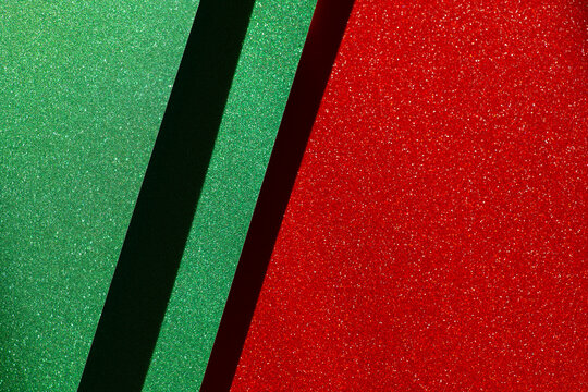 Diagonal red and green glitter surfaces separated by a dark stripe, suitable for modern Christmas posters, seasonal advertising, festive invitations, social media graphics and retail promotions. 