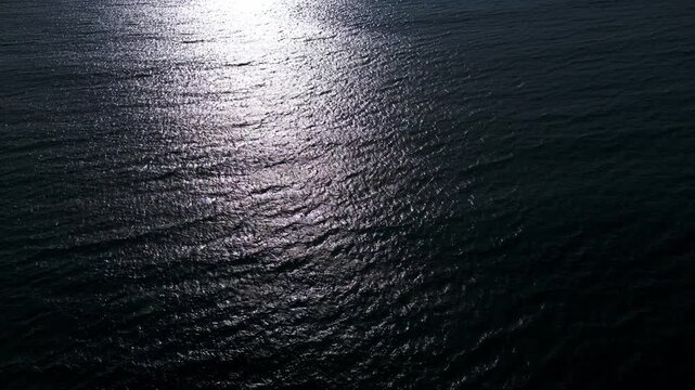 Aerial View of Calm Ocean Water Surface with Golden Sun Reflection at Sunset