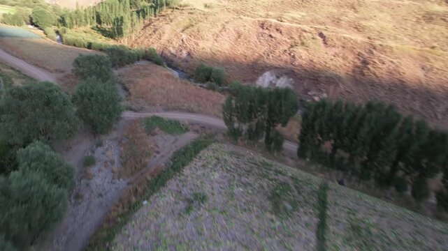 Winding dirt track on Chalus Road weaves through trees and dry slopes, a rural mountain path above a small watercourse. Ideal for travel, tourism, and nature stock Iran Alborz mountains.