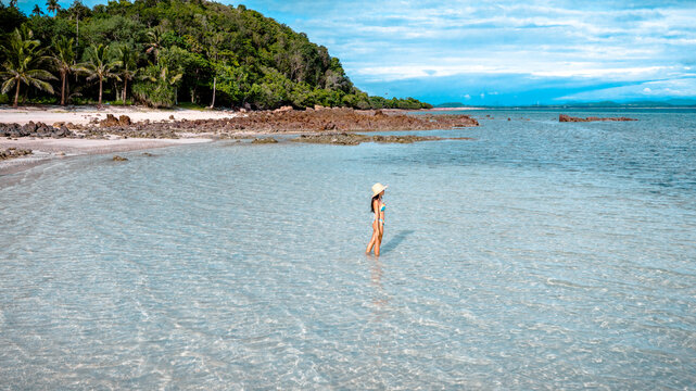 Woman tourist stay happy moment at the edge of the sea beach under shallow of the crystal clear water in summer trip on tropical island island