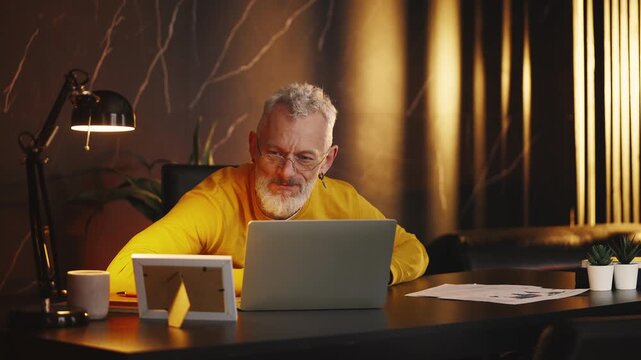 Nervous middle-aged businessman works on laptop, stressed by failed project