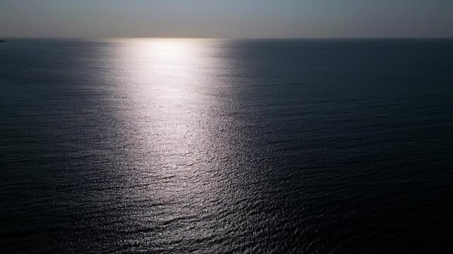 Aerial View of Calm Ocean Water Surface with Golden Sun Reflection at Sunset