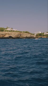 Vertical boat cruise passing a rocky Mallorca headland