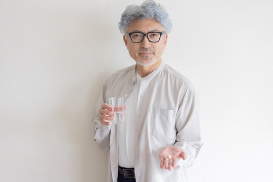 水と薬を手に健康管理をするシニア男性
