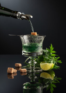 Absinthe is poured from an vintage bottle into a glass.
