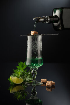 Absinthe is poured from an vintage bottle into a glass.