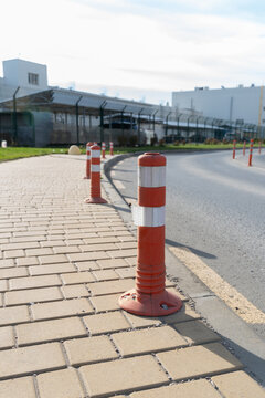 Orange delineator posts along the access road of an industrial facility.