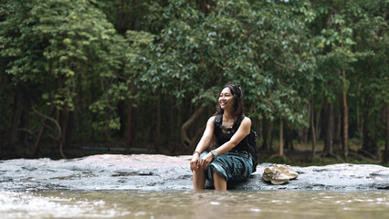 Fototapeta premium Happy Woman Backpacker Relaxing with Feet in River Water Outdoors