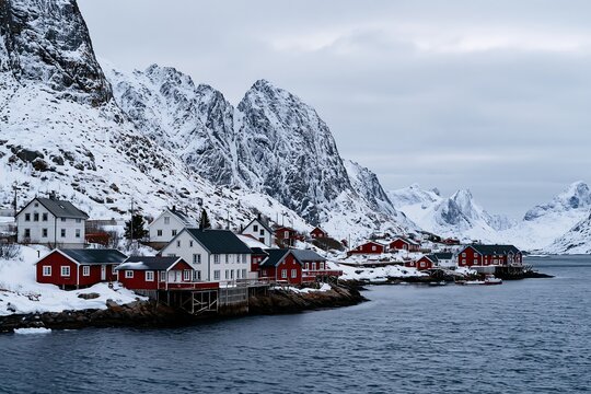 Winter landscape with red houses and snow covered mountains in Norway