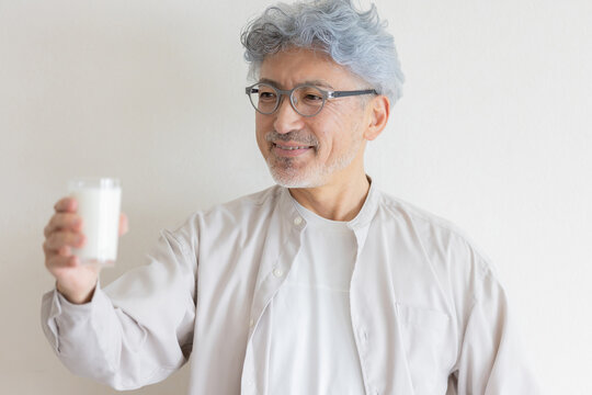 牛乳を手に笑顔を見せるシニア男性の健康的なライフスタイル
