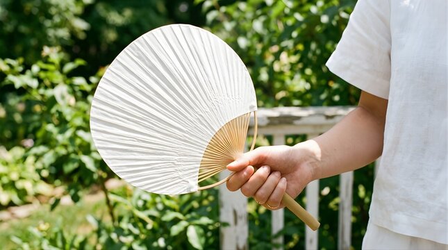 Woman holding a traditional white hand fan outdoors on a sunny day