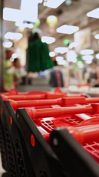 Close-up of nested red shopping carts or baskets lined up in a row against the blurred background of checkout counters in a grocery store or supermarket. Retail shopping, commerce concept.